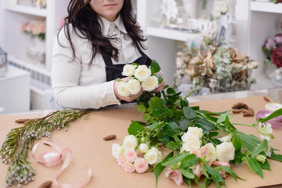 Florist arranging bouquets with floral foliage. 