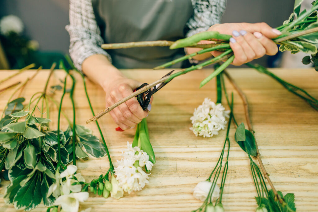 Female florist cutting stems and filler greenery for a floral arrangement.