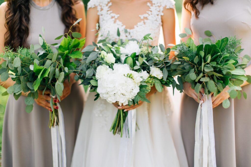 3 women holding bouquets with vibrant foliage throughout. Wholesale greenery.