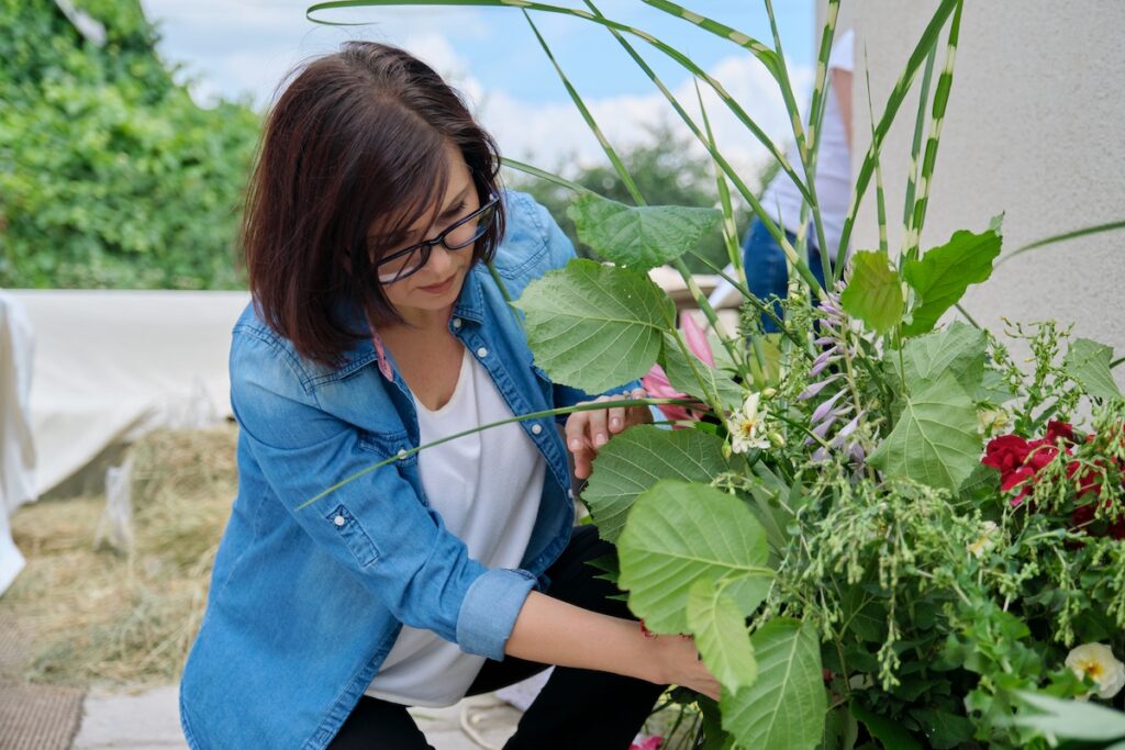  A woman looking down at a large bouquet with various foliage types and flowers.