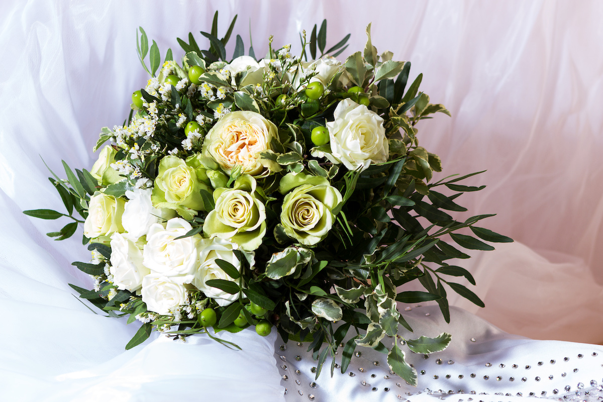 A monochrome bouquet of flowers with mostly green flowers and foliage and some accent white flowers.